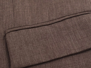 Gros plan sur le tissu texturé marron et les coutures de poche d'un blazer pour femme