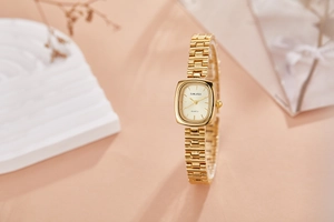 Detailed close-up of a vintage gold women's watch with rectangular case on stone props