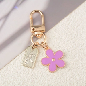 Golden flower keychain with purple enamel pendant and engraved good luck metal plate