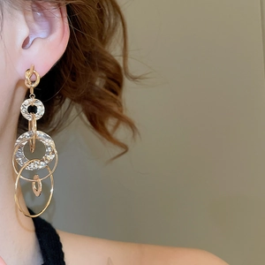 Detailed close-up of golden knotted tassel earrings with hammer-textured metal finish