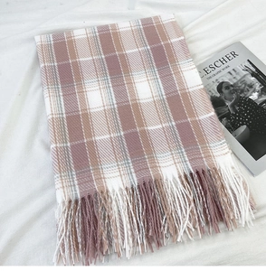Detail of pink and beige plaid scarf with soft tassels on a white fabric background