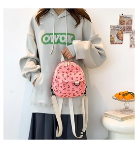 Close-up of pink corduroy mini backpack featuring cute red cherry prints and front pocket