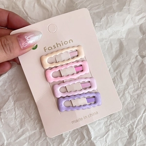 Set of four wavy-edged pink hair clips in various shades on a branded display card