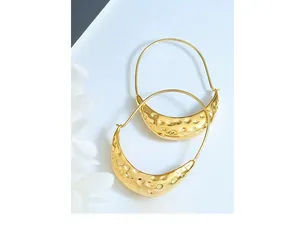 Macro view of golden crescent earrings showing detailed hammered texture on stainless steel