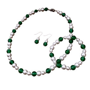 Vintage jewelry set with green cat eye stones and white pearls on a clean white background