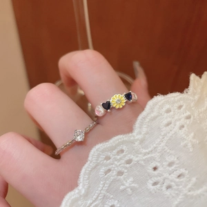 Detailed view of silver rings featuring enamel flower and yin-yang symbols on fingers