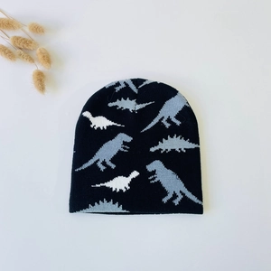 Detail showing knit beanie texture with gray and white dinosaur silhouette patterns