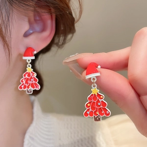 Detail of Christmas tree and Santa hat earrings with pearls and red enamel finish