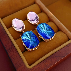 Detail of vintage gold earrings with pink and blue gemstones in a brown velvet box