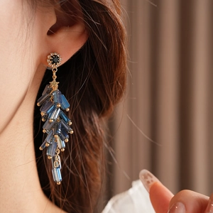 Close-up of blue tassel drop earrings with star accent on model in elegant pose