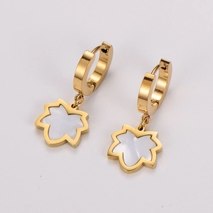 Macro view of golden earring with flower clover shape and white shell inlay detail