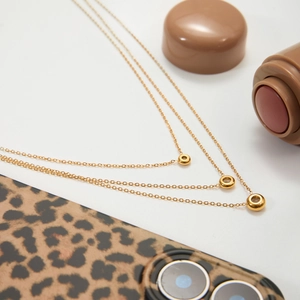 Three-layer gold stainless steel necklace with hollow circular charms on white background