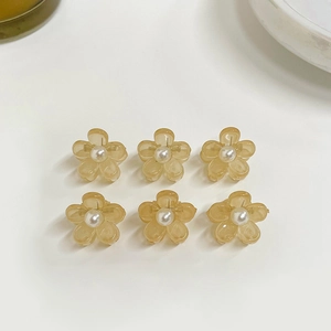 Detail of six amber flower hair claws with central pearl accents and glossy finish