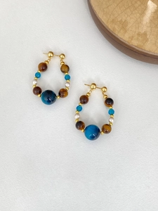 Détail de boucles d'oreilles pendantes en perles bleues, perles d'ambre et tiges en argent