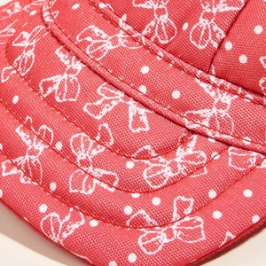 Dettaglio della visiera del cappello rosso per cani con fiocchi bianchi e cuciture solide