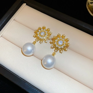 Macro view of gold snowflake earrings with sparkling crystals and large white pearls