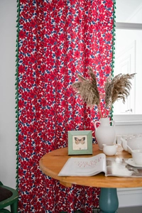 Detail view of red and blue floral cotton linen curtain with green tassel fringes