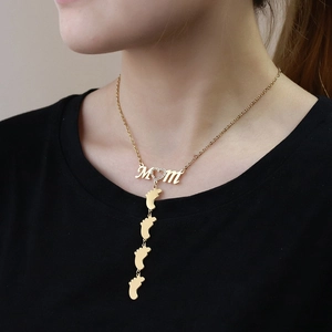 Close-up of a gold MOM necklace with a crystal heart and four baby feet pendants