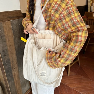 Detail view of cream striped tote bag with interior pocket and drawstring closure design