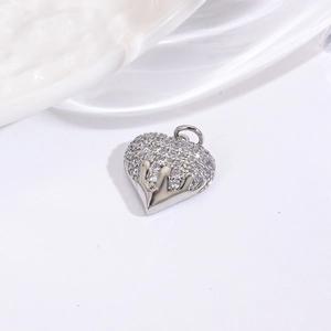 Macro shot of silver heart pendant with shimmering clear zircons on a white surface