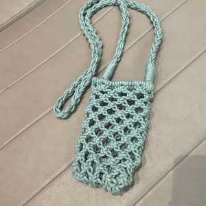Close-up of mint green hand-woven cotton phone bag with thick braided strap detail