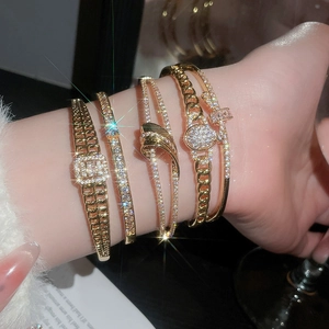 Vue détaillée de quatre bracelets dorés de luxe avec zircone sur un poignet féminin