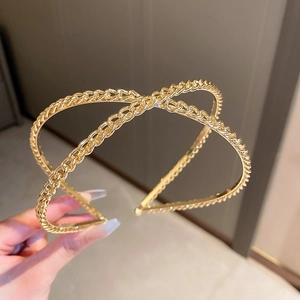 Détail d'un serre-tête doré à maillons avec design croisé en X et strass brillants