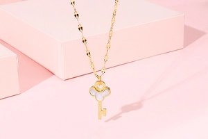 Detail of clover key pendant necklace in gold with white shell inlay and lip chain