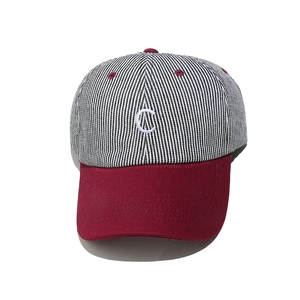 Gros plan sur la broderie C de la casquette rayée avec visière rouge bordeaux