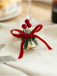 Detail of Christmas napkin ring with red berries, velvet bow and golden bells
