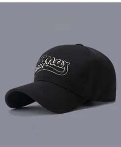 Close-up of beige embroidered lettering on a black cotton baseball cap showing fabric texture