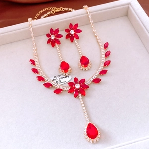 Detailed macro view of gold-plated flower jewelry set with red zircon and crystal tassels