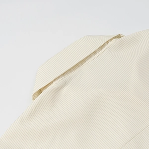 Détail du col d'une chemise rayée beige montrant les coutures et la texture du tissu respirant