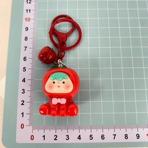Detailansicht eines roten Frucht-PVC-Schlüsselanhängers mit Glocke auf Messmatte
