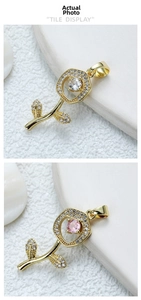 Detail of 18k gold rose pendant necklace with crystal inlay on white stone surface