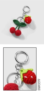 Detail of handmade crochet strawberry keychain with red yarn fruit and green leaves