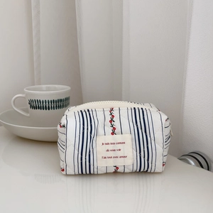 Detail of floral quilted cotton pouch with red cherry pattern and blue stripes