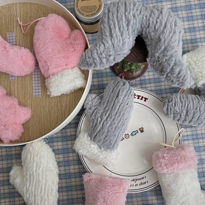 Détail de décorations de gants de Noël en peluche rose, blanc et gris sur plateau