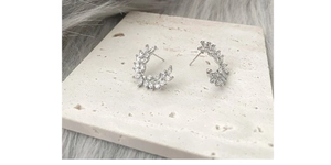 Detail showing elegant silver crescent wheat ear earrings with zircon inlay on stone base