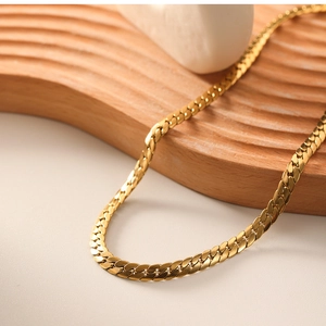 Macro shot of flat 18k gold plated stainless steel snake chain on textured wooden tray
