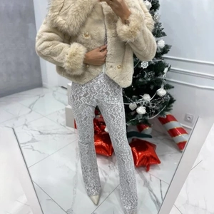 Detail of elegant beige faux fur coat with gold buttons and white lace jumpsuit outfit