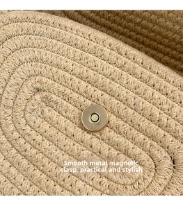 Detail of smooth metal magnetic snap closure on woven straw shoulder bag for beach wear
