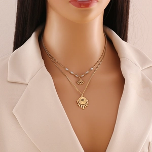 Detail view of double-layered gold stainless steel necklace with evil eye and sun pendants