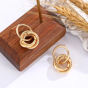 Minimalist interlocking gold hoop earrings for women presented on a wooden display stand