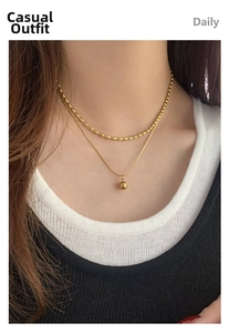 Détail d'un collier double épaisseur doré avec pendentif boule sur mannequin
