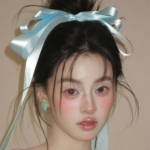 Light blue large satin bow hair clip worn by a model with elegant emerald earrings