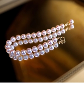 Macro shot of pink pearl bracelet with mirror reflection and golden metal clasp