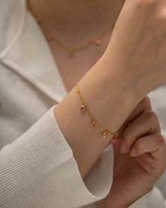 Gros plan d'un collier en or avec des pendentifs en pierres roses rondes et carrées sur modèle