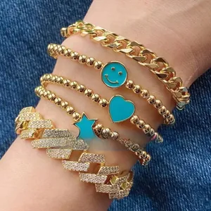 Detail of five-piece gold bracelet set with turquoise smile and heart charms on denim