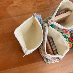 Detailed interior of floral canvas pouches showing storage of makeup kits and zippers